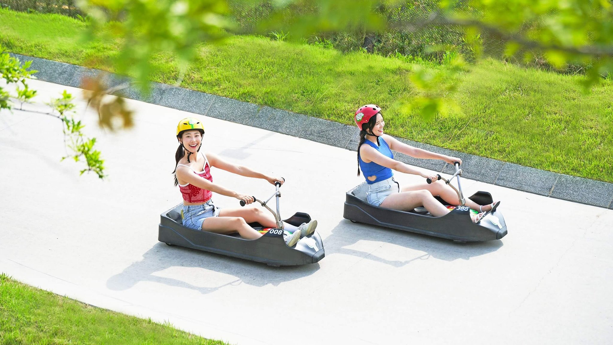 Two ladies smile as they descend the Skyline Luge Busan tracks.