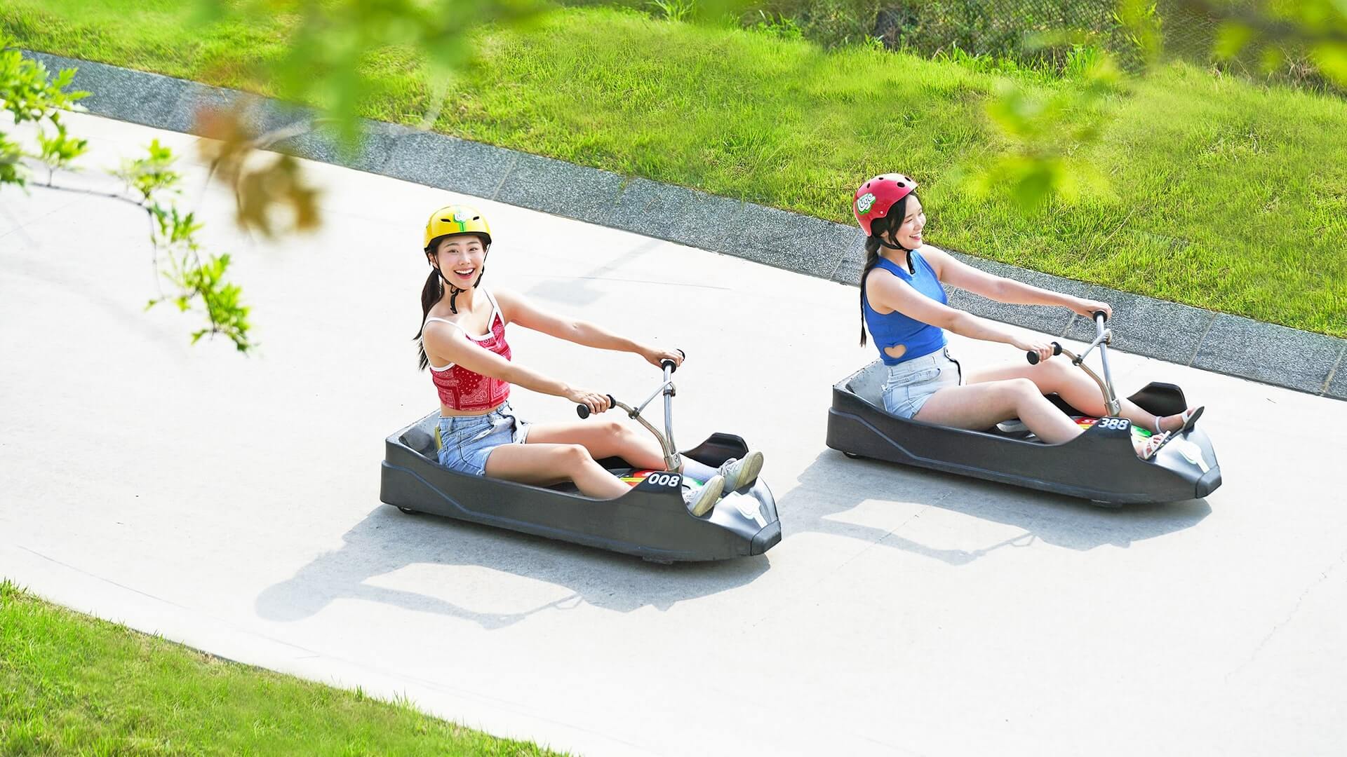 Two ladies smile as they descend the Skyline Luge Busan tracks.