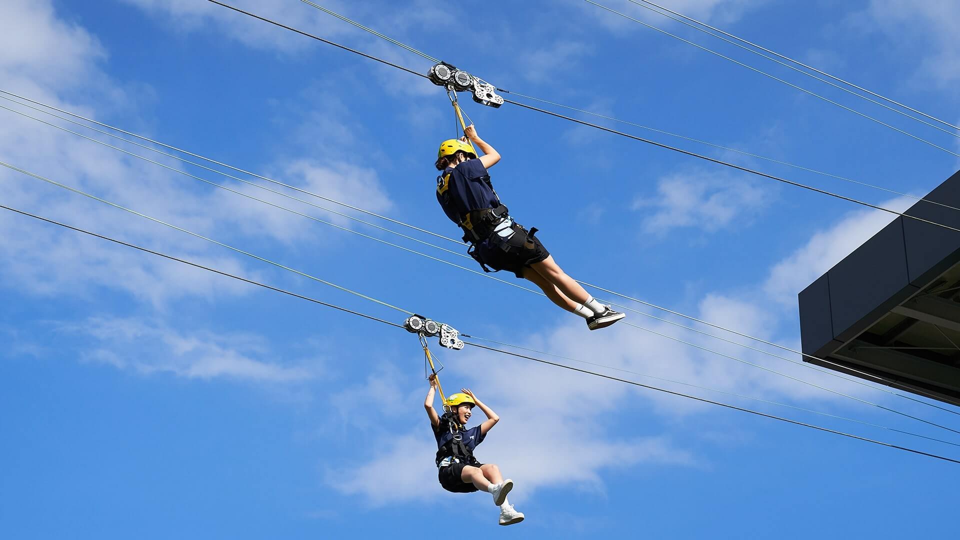 Two friends race down the Hyfly zipline next to eachother.